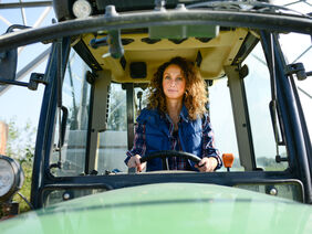 beautiful woman female farmer driving tractor in countryside field